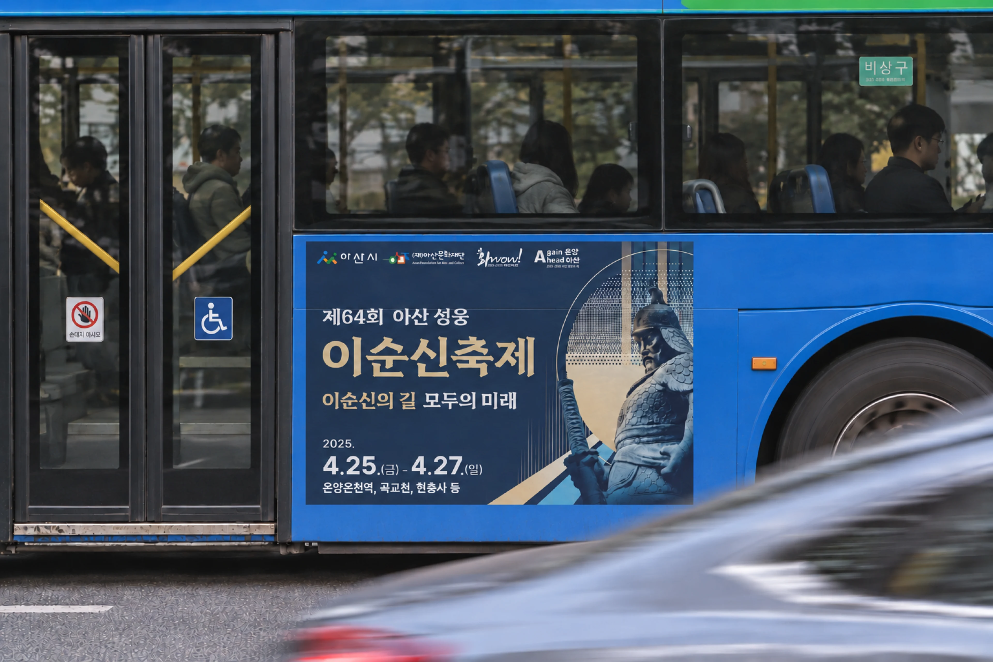아산 시내버스 옆면에 붙은 이순신축제 광고, 앞으로 승용차가 흐릿하게 지나가는 장면 (AI로 구성한 이미지)
