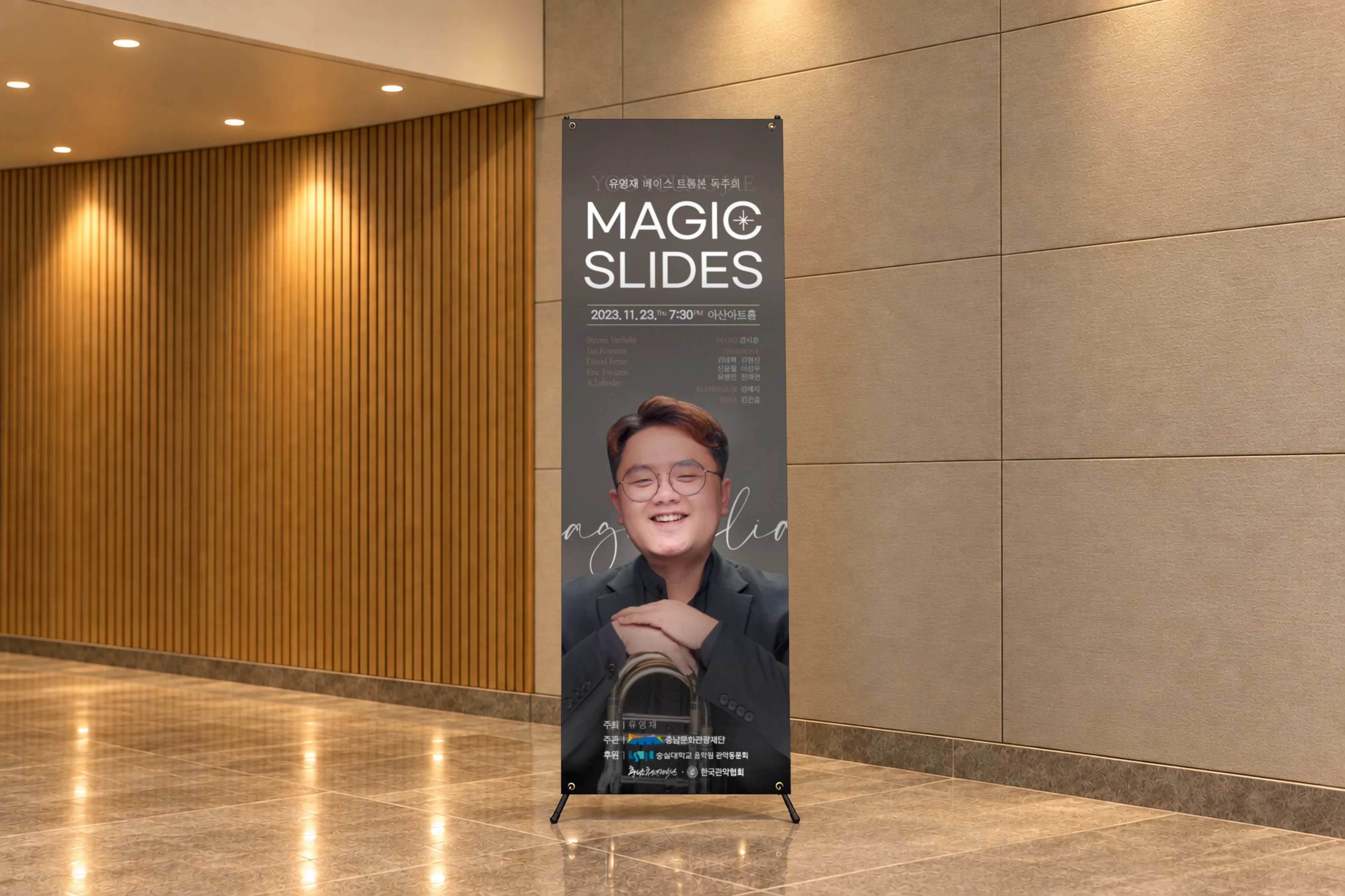 공연장 로비 나무 벽 앞에 세운 세로 배너. 위쪽에 MAGIC SLIDES 글자, 아래에 연주자 사진.